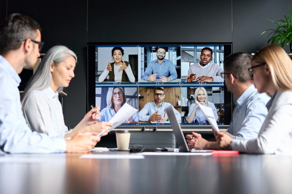 global corporation online videoconference in meeting room with diverse people sitting in modern office and multicultural multiethnic colleagues on big screen monitor. business technologies concept.